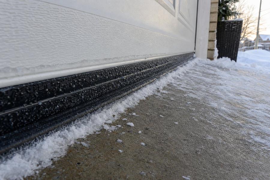 Garage door bottom seal frozen to a snowy concrete driveway after a GTA ice storm
