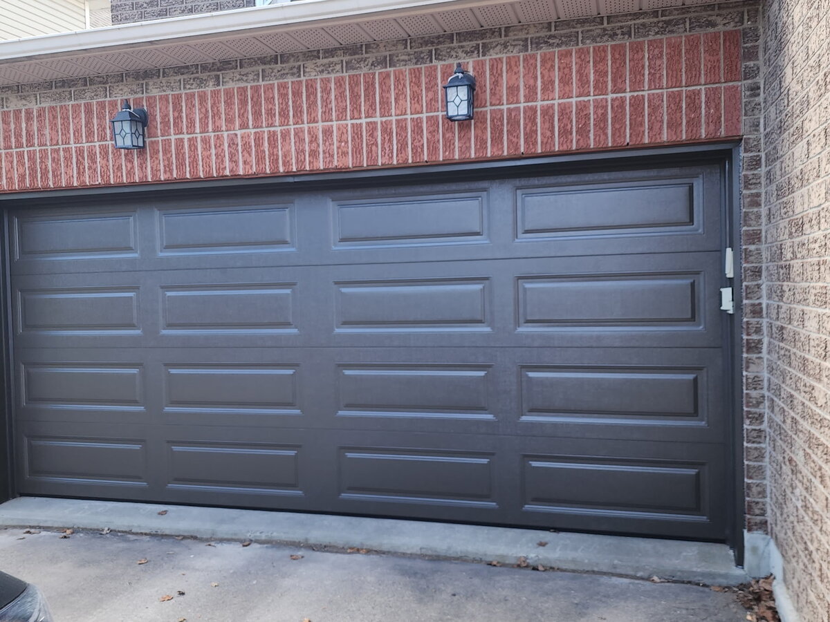 Charcoal grey raised-panel double garage door on a two-tone brick home