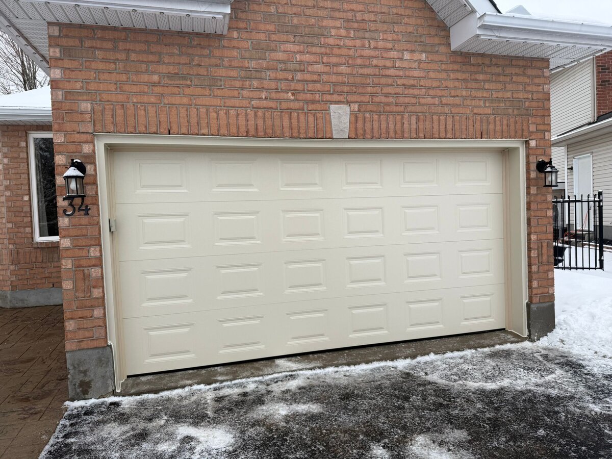 Almond raised-panel double garage door on a red brick home