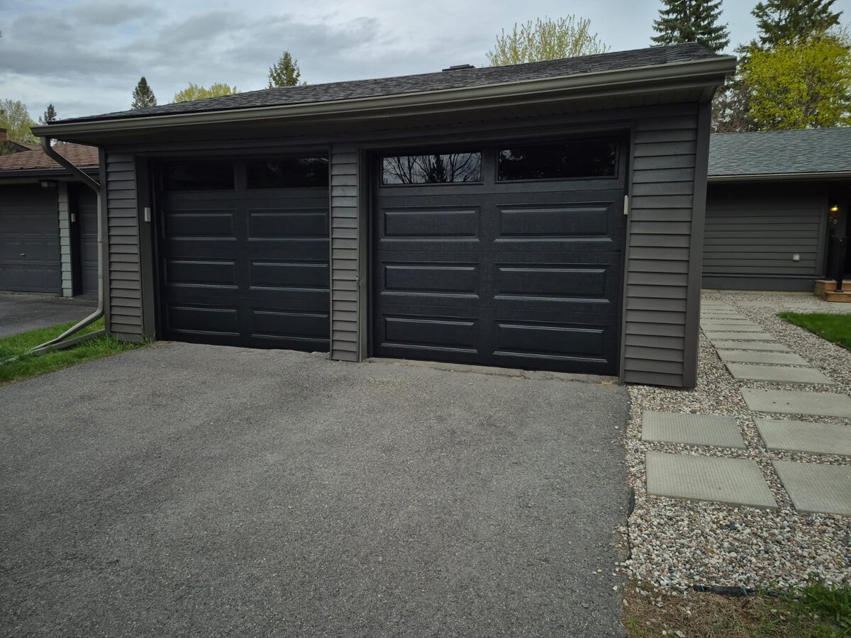 Black modern double garage door on a detached garage with a long driveway
