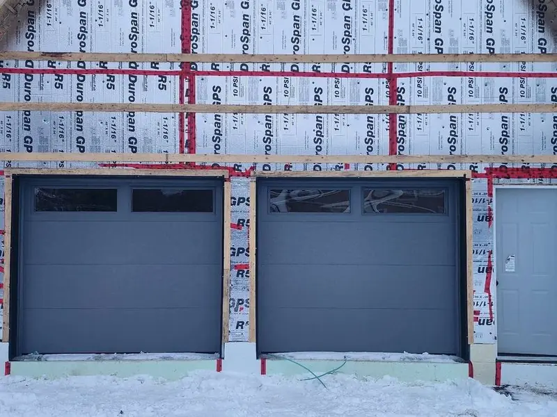 Two black modern garage doors on a new-construction detached garage