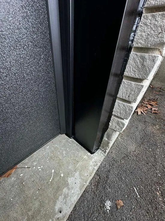 DPS Garage Doors dark aluminum capping finished around a garage door jamb against stone in the GTA